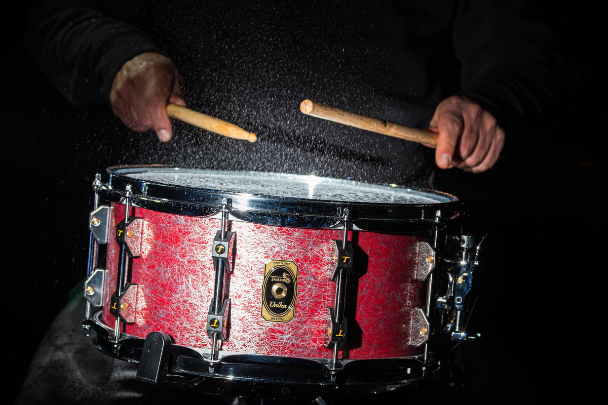 A drummer striking a red Tamburo snare drum